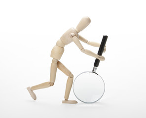 Wooden man with magnifying glass on white background