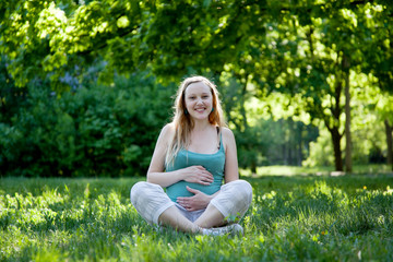 Naklejka na ściany i meble Beautiful pregnant woman relaxing in the park