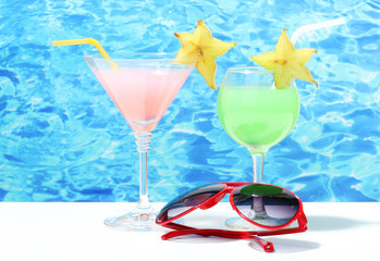 Glasses of cocktails on table on blue sea background