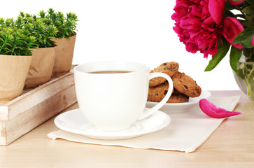 cup of coffee, cookies and flowers on table in cafe