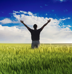 man standing on the green field under blue sky