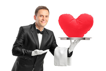 Butler holding a tray with a red heart shape object on it