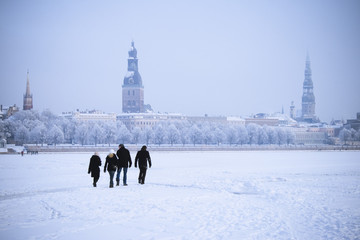 People crossing a frozen river in  Riga, Latvia - obrazy, fototapety, plakaty