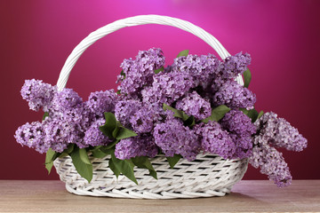 beautiful lilac flowers in basket on red background