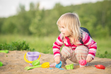 Adorable baby with bag play with toys on sandbox