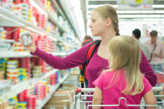 Mother and daughter shopping in milk section in supermarket