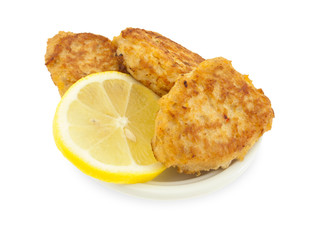 Fish cutlets with a lemon on the white plate.
