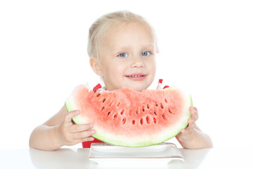 Little smiling blonde girl eating a watermelon