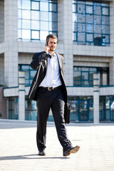 businessman on the phone coming out of a building