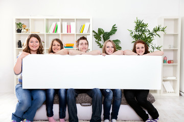Happy smiling group of friends showing blank placard board