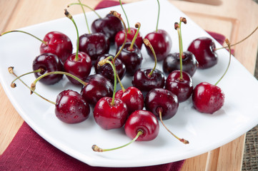 Horizontal shot of a glass plate full of fresh sweet cherries