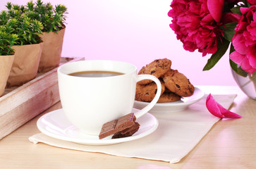 cup of coffee, cookies, chocolate and flowers on table in cafe