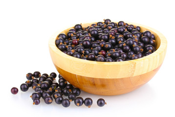Black currant in wooden bowl isolated on white