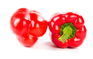 two fresh red peppers on white
