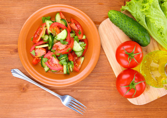 Fresh salad with tomatoes and cucumbers on wooden background
