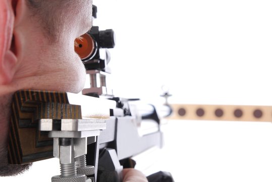 Marksman sighting down the barrel of an air rifle