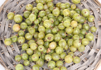 Green gooseberry on wicker mat close-up