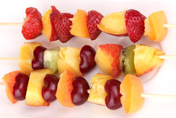 Mixed fruits and berries on skewers close-up