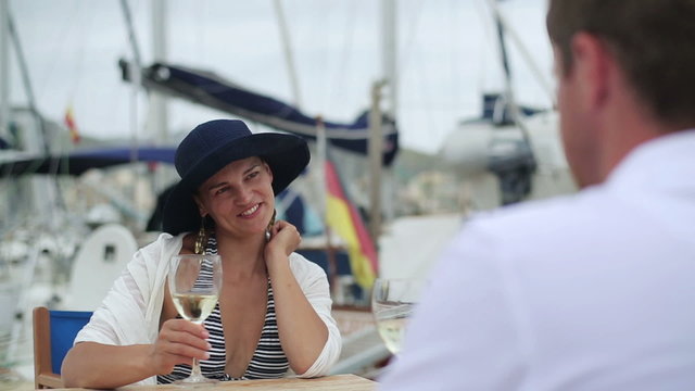 Young couple drinking wine at marina, steadycam shot
