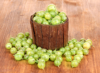 Green gooseberry in wooden cup on wooden background