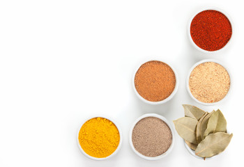  Different spices in white bowls isolated on white background.