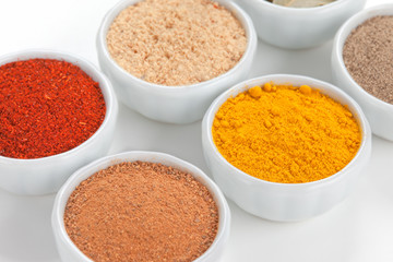  Different spices in white bowls isolated on white background.