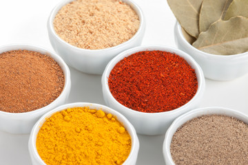  Different spices in white bowls isolated on white background.