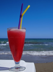 Glass with strawberry drink against the sea.