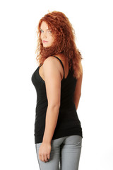 Naklejka premium Young woman with long red hair is looking back.