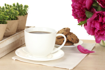 cup of coffee, cookies and flowers on table in cafe