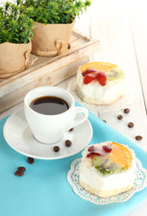cup of coffee and sweet cakes with fruits on wooden table