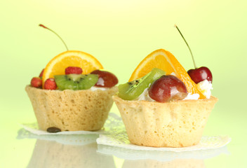 sweet cakes with fruits on green background