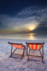 couples of wood teak chairs beach and sun set scene