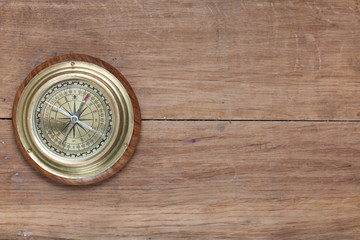 Bronze compass on the old wooden background