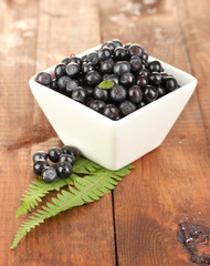 fresh blueberries in white bowl on wooden background close-up