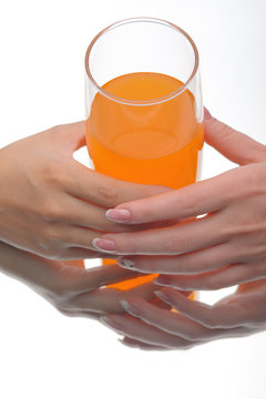 Two hands holding glass of orange fluid