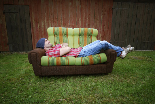 L&auml;chelnder Mann liegt auf einer Couch