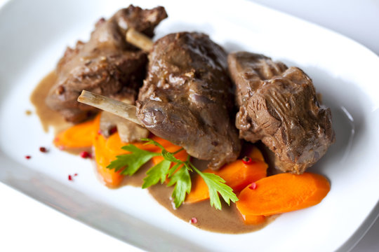 Civet de li&egrave;vre en sauce et carottes dans un plat blanc