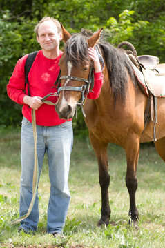 Handsome smiling man with horse in the forest