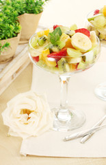 Fresh fruits salad and strawberries on wooden table