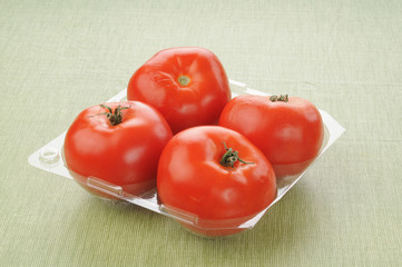Plastic container with four tomatoes