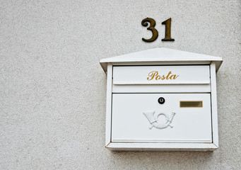 White mail box on a wall.