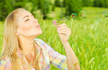 Pretty woman blowing soap bubbles in park