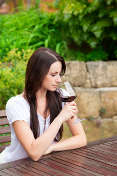 Frau trinkt Wein im Garten
