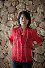 asain woman in red shirts standing in font of rock wall