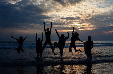 big family jumping on the beach at dusk