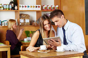 Paar schaut auf Tablet Computer im Café
