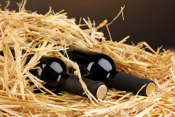 Bottles of great wine on hay on brown background
