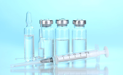 Syringe and medical ampoules on blue background