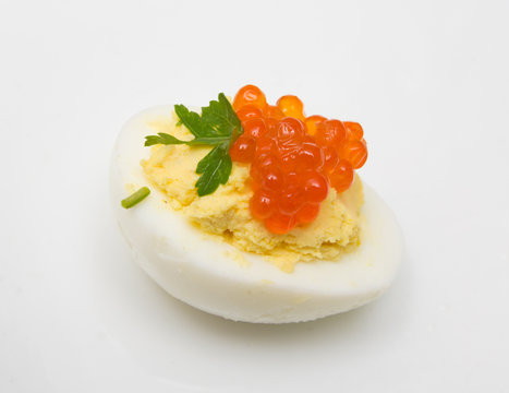 Egg with red caviar and parsley on a white background